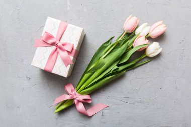 Pembe lale çiçekleri ve hediye ya da renkli masa arkaplanındaki hediye kutusu. Anneler günü, doğum günü, kadınlar günü, kutlama konsepti. Metin üstü görünümü için boşluk.