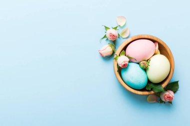 Mutlu Paskalyalar. Renkli masada sarı güllerle birlikte Paskalya yumurtaları. Doğal boyalı renkli yumurtalar arkaplan arkaplan görünümü kopya alanı ile.