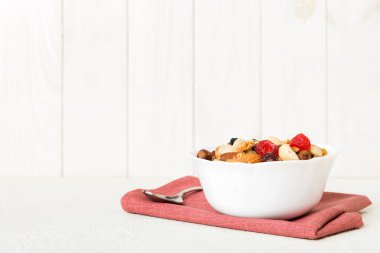 Sağlıklı bir kahvaltı hazırlıyorum. Bir kasede çeşitli kurutulmuş meyve ve fındıklı granola. Sağlıklı tatlı kavramı. Düz konum, kopyalama alanı olan üst görünüm.