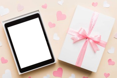 Gift box of open tablet for the holidays with a bow top view.