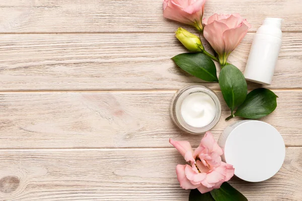 Ahşap zemin üzerinde yeşil yapraklar olan organik kozmetik ürünler. Uzayı kopyala, düz yat.