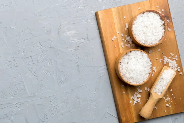 Ahşap bir arka planda ahşap bir kase tuz kristali. Kırsal kaselerdeki tuz, fotokopi alanı olan üst görünüm.