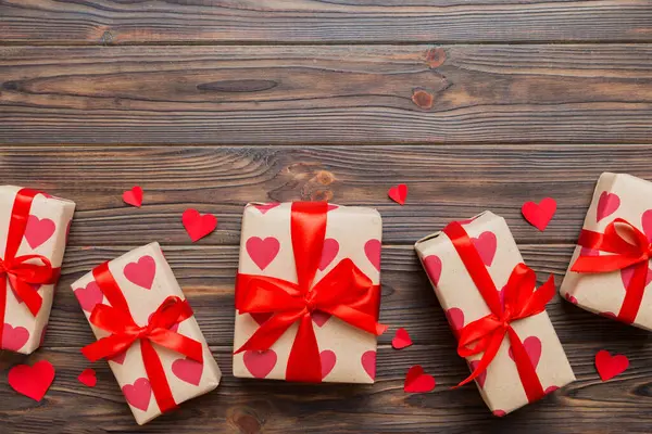 Top view photo of valentine day decorations gift box with red ribbon bow on colored background. Holiday gift boxes with top view.