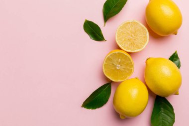 Renkli arka planda yeşil yapraklı taze limonlar, üst görünüm, metin için boşluk.