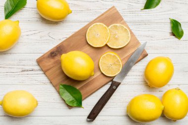 Kesme tahtasındaki taze ve olgun limonlar için fotokopi alanı olan üst manzara. Sağlıklı yemek geçmişi. Limon ve limon dilimlerinin, sıkacağı ve bıçak renginde arka planı çok zarif..