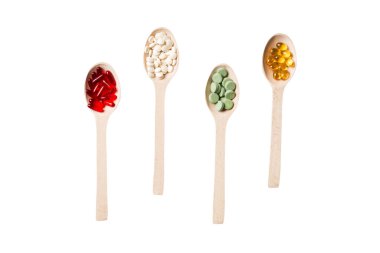 Renkli arka planda tahta kaşıkta vitamin ve mineral haplarının üst görünümü. Muhtelif ilaç haplarının en üst görüntüsü. Beslenme takviyesi sağlık ürünleri.