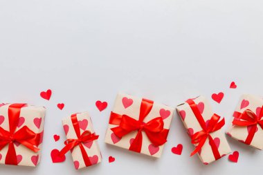 Top view photo of valentine day decorations gift box with red ribbon bow on colored background. Holiday gift boxes with top view.