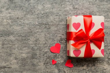 Top view photo of valentine day decorations gift box with red ribbon bow on colored background. Holiday gift boxes with top view.