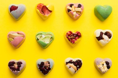 chocolate sweets in the form of a heart with fruits and nuts on a colored background. top view with space for text, holiday concept.