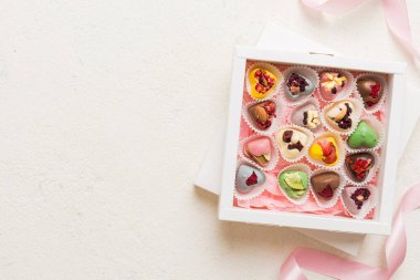 Holiday composition: sweet candy, with gift boxes with bow and chocolate hearts, photo template, background. Top View with copy space on colored background.