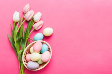 Mutlu Paskalya kompozisyonu. Renkli masada sarı laleli sepetli Paskalya yumurtaları. Doğal boyalı renkli yumurtalar arkaplan arkaplan görünümü kopya alanı ile.