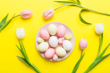 Mutlu Paskalya kompozisyonu. Renkli masada sarı laleli sepetli Paskalya yumurtaları. Doğal boyalı renkli yumurtalar arkaplan arkaplan görünümü kopya alanı ile.
