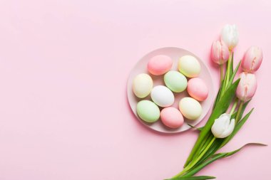 Mutlu Paskalya kompozisyonu. Renkli masada sarı laleli sepetli Paskalya yumurtaları. Doğal boyalı renkli yumurtalar arkaplan arkaplan görünümü kopya alanı ile.