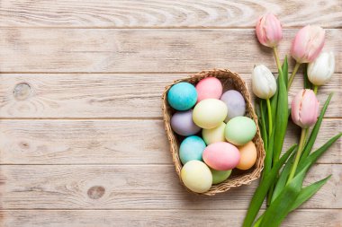 Mutlu Paskalya kompozisyonu. Renkli masada sarı laleli sepetli Paskalya yumurtaları. Doğal boyalı renkli yumurtalar arkaplan arkaplan görünümü kopya alanı ile.