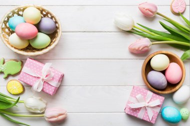 Yumurtalı Paskalya çerçevesi, renkli bir arka planda hediye kutusu ve lale. Minimum konsept. Üst Manzara Mutlu Paskalyalar kompozisyonu. Metin için yerin bir kopyasına sahip kart.