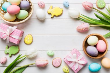 Yumurtalı Paskalya çerçevesi, renkli bir arka planda hediye kutusu ve lale. Minimum konsept. Üst Manzara Mutlu Paskalyalar kompozisyonu. Metin için yerin bir kopyasına sahip kart.