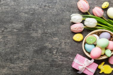 Yumurtalı Paskalya çerçevesi, renkli bir arka planda hediye kutusu ve lale. Minimum konsept. Üst Manzara Mutlu Paskalyalar kompozisyonu. Metin için yerin bir kopyasına sahip kart.