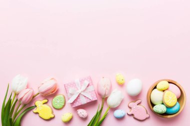 Yumurtalı Paskalya çerçevesi, renkli bir arka planda hediye kutusu ve lale. Minimum konsept. Üst Manzara Mutlu Paskalyalar kompozisyonu. Metin için yerin bir kopyasına sahip kart.