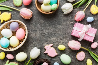 Yumurtalı Paskalya çerçevesi, renkli bir arka planda hediye kutusu ve lale. Minimum konsept. Üst Manzara Mutlu Paskalyalar kompozisyonu. Metin için yerin bir kopyasına sahip kart.