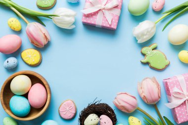 Yumurtalı Paskalya çerçevesi, renkli bir arka planda hediye kutusu ve lale. Minimum konsept. Üst Manzara Mutlu Paskalyalar kompozisyonu. Metin için yerin bir kopyasına sahip kart.