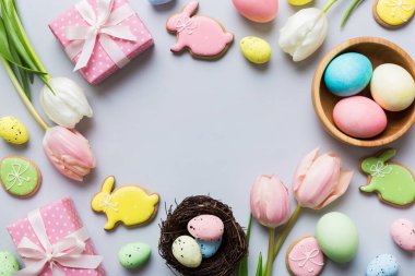 Yumurtalı Paskalya çerçevesi, renkli bir arka planda hediye kutusu ve lale. Minimum konsept. Üst Manzara Mutlu Paskalyalar kompozisyonu. Metin için yerin bir kopyasına sahip kart.
