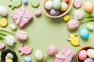 Yumurtalı Paskalya çerçevesi, renkli bir arka planda hediye kutusu ve lale. Minimum konsept. Üst Manzara Mutlu Paskalyalar kompozisyonu. Metin için yerin bir kopyasına sahip kart.