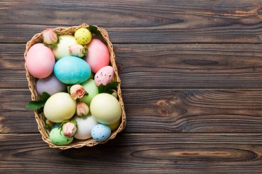 Mutlu Paskalyalar. Renkli masada sarı güllerle birlikte Paskalya yumurtaları. Doğal boyalı renkli yumurtalar arkaplan arkaplan görünümü kopya alanı ile.