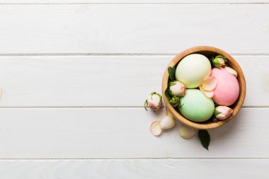 Mutlu Paskalyalar. Renkli masada sarı güllerle birlikte Paskalya yumurtaları. Doğal boyalı renkli yumurtalar arkaplan arkaplan görünümü kopya alanı ile.