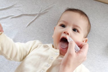 Annesi oğlu için burun damlası damlatıyor. Bebek sağlığı konsepti üst görünüm.