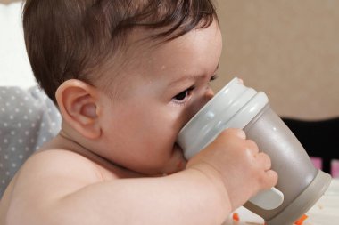 Yakışıklı, tatlı bir çocuk. Masada oturuyor. Şişeden su içiyor..