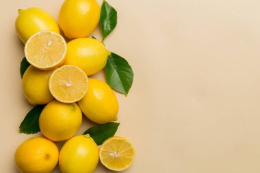 Renkli arka planda yeşil yapraklı taze limonlar, üst görünüm, metin için boşluk.