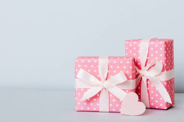 gift box with red bow and red heart on colored background. Perspective view. Flat lay.