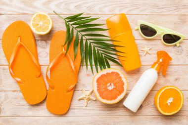 Arka planda plaj aksesuarları olan parmak arası terliklerin üst görünümü. Tropik yaz tatili konsepti.