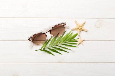 Masa arkasında deniz kabuğu olan güneş gözlükleri. Yaz arkaplanında güneş gözlüğü. Metin için kopyalama alanı olan üst görünüm düzlüğü.