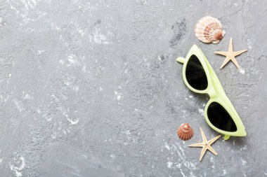 Masa arkasında deniz kabuğu olan güneş gözlükleri. Yaz arkaplanında güneş gözlüğü. Metin için kopyalama alanı olan üst görünüm düzlüğü.