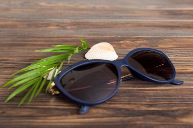 Masa arkasında deniz kabuğu olan güneş gözlükleri. Yaz arkaplanında güneş gözlüğü. Metin için kopyalama alanı olan üst görünüm düzlüğü.