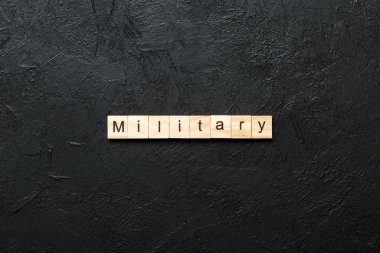 Tahta bloğa yazılmış militanca bir kelime. Çimento sehpası üzerindeki MILITARY metin desing, konsept.