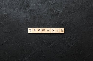 Ahşap bloğa yazılmış takım çalışması kelimesi. Deksing, konsept için çimento masadaki takım çalışması metni.