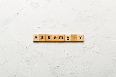 Tahta bloğa yazılmış bir kelime. Çimento sehpasında senin desing, konsept için ASSEMBLY metin.