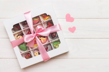 Valentine day composition: sweet candy, with gift boxes with bow and red felt hearts, photo template, background. Top View with copy space.