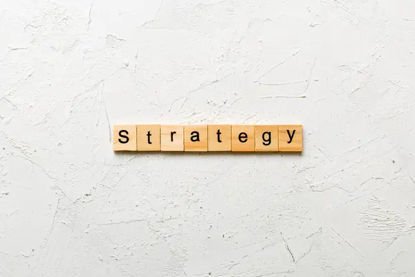 Tahta blokta STRATEGY kelimesi yazıyor. Beton masadaki STRATEGY metin desing, konsept için.