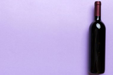 Renkli masada bir şişe kırmızı şarap. Düz konum, üst görünüm kopyalama alanı.