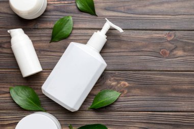 Ahşap zemin üzerinde yeşil yapraklar olan organik kozmetik ürünler. Uzayı kopyala, düz yat.