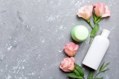 Kozmetik ürünleri ve çimento arka planında güzel güller olan kompozisyon. Uzayı kopyala, düz yat.