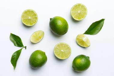 Yeşil yapraklı kireç meyveleri ve beyaz arka planda yarım dilim kesilmiş. Üst Manzara. Kopyalama alanı olan düz.