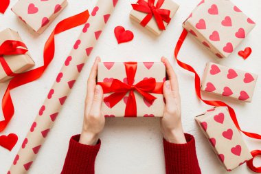 Give a gift on Valentine Day.Valentine gift. Beauty Woman hands holding Gift box with red bow over holiday background.