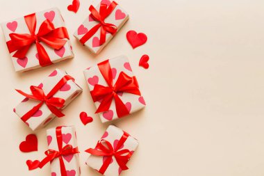 Top view photo of valentine day decorations gift box with red ribbon bow on colored background. Holiday gift boxes with top view.