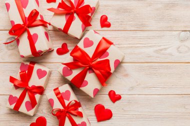 Top view photo of valentine day decorations gift box with red ribbon bow on colored background. Holiday gift boxes with top view.