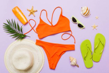 Kadın mayosu ve plaj aksesuarları düz manzarada yatıyordu. Renkli arka planda bikinili üst manzara. Tatil kavramı kopyalama alanı.