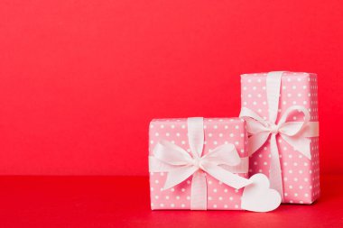 gift box with red bow and red heart on colored background. Perspective view. Flat lay.